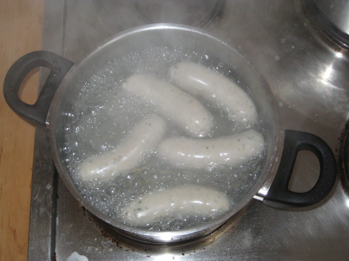 Weisswurst sausages heating in a pan of hot water