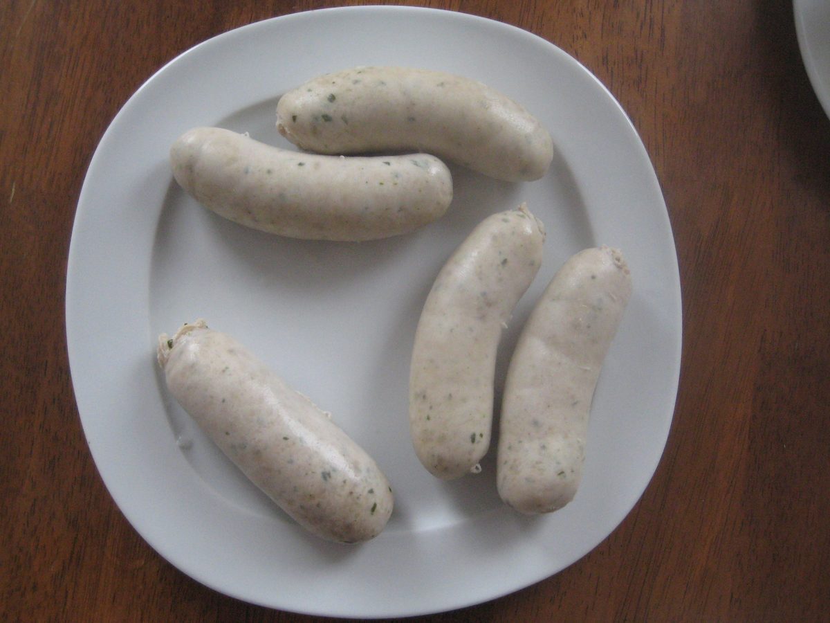 Four Weisswurst sausages on a white plate