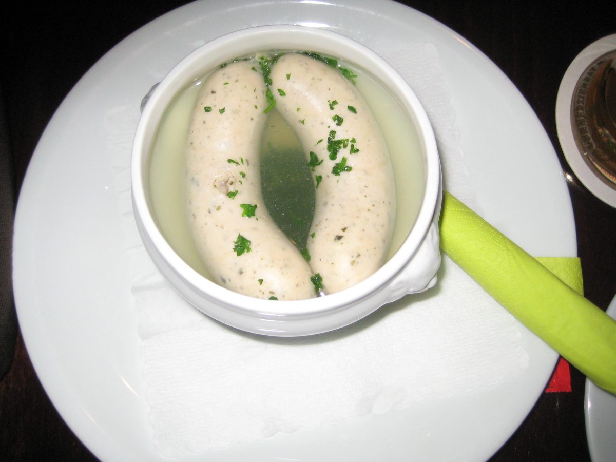 Two Weisswurst sausages in a tureen of hot water